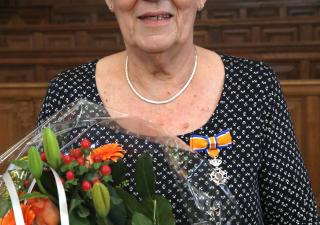Vrouw met zwarte jurk, bloemen en oranje lintje