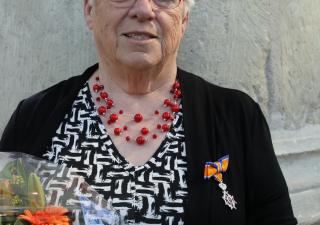 Vrouw met zwart jasje en oranje lintje